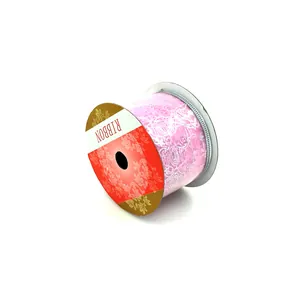 Dettaglio di un rotolo di nastro rosa con motivo floreale bianco su rocchetto