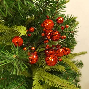 Close-up van rode kerstbessen met glitters op takken van een kunstmatige dennenboom.