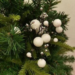 Close-up van kunstmatige witte en zilveren bevroren bessen op een kerstboomtak voor decoratie.