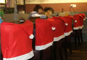 Rode non-woven kerstmuts stoelhoezen voor feestelijke kerstversiering aan de eettafel