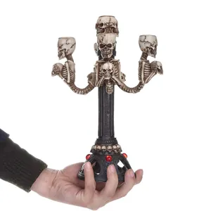 Vista en mano de un candelabro gótico de calavera de resina con detalles de esqueleto.