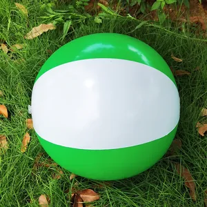 Detailed close-up view of a 36cm green and white inflatable beach ball on lush green grass