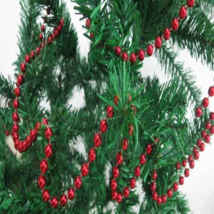 Close-up of red metallic bead garland draped on green Christmas tree branches.
