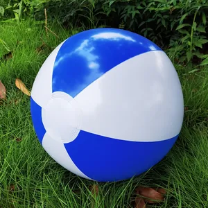 Inflatable blue and white striped beach ball resting on lush green grass outdoors