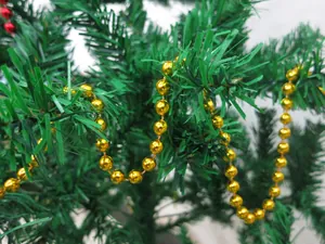 Close-up detail of a shiny gold bead chain garland hanging on a green Christmas tree