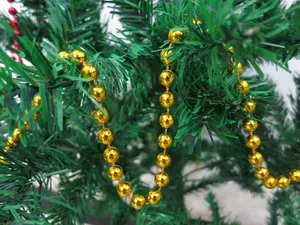 Macro view of a shiny golden beaded garland decorating a green festive Christmas tree.