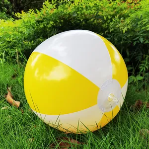 Detail of a yellow and white inflatable beach ball resting on lush green grass.