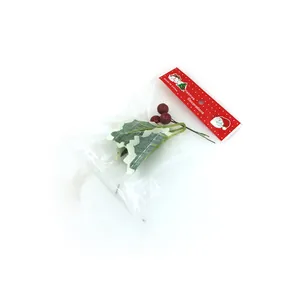 Detail view of artificial red Christmas berries with green holly leaves in packaging