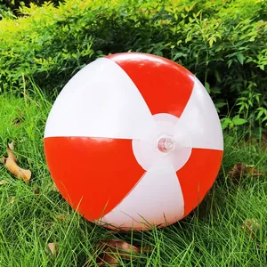 Close-up view of a 36cm red and white inflatable beach ball resting on lush green grass.