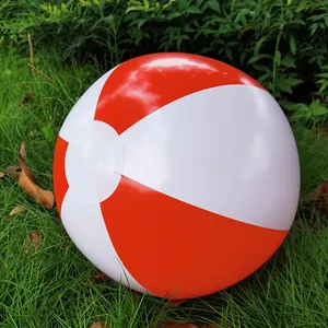 Close-up of a red and white inflatable beach ball on green grass for outdoor summer fun.