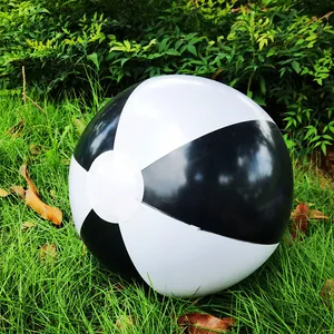 Close-up of a 36cm black and white inflatable beach ball on green grass lawn.