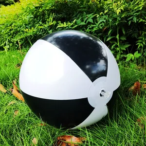Detail of a 36cm black and white inflatable beach ball resting on lush green grass.