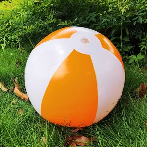 A 36cm inflatable orange and white striped beach ball resting on lush green grass outdoors