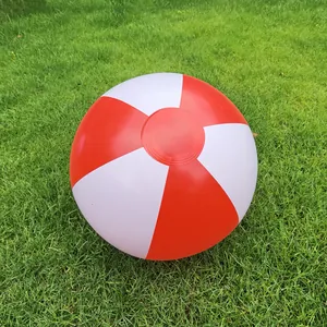 Close-up of a 36cm red and white inflatable beach ball resting on green grass