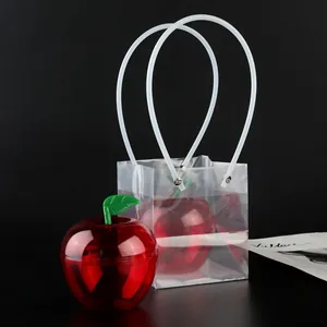Close-up of apple-shaped red candy box with transparent PVC gift bag on black background