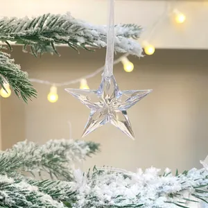 Transparenter Acryl Stern Weihnachtsbaumschmuck mit Facettendesign an verschneitem Ast.