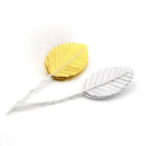 Detailed view of artificial gold and silver fabric leaves with white wire stems.