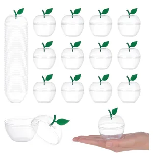 Clear plastic apple-shaped candy box with green leaf detail, shown in hand for scale.