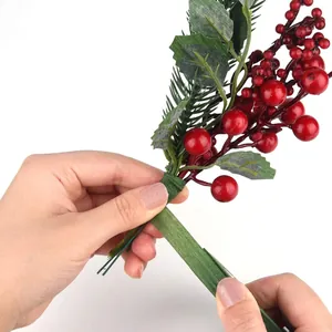 Detailed macro view of green floral tape being wrapped around artificial berry stems for DIY crafts