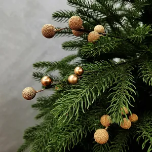 Gros plan détaillé de baies de Noël dorées texturées et lisses sur un sapin de Noël