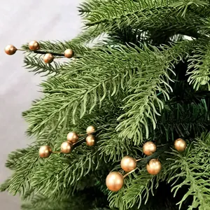 Détail d'une branche de pin avec des baies en cuivre pour la décoration de Noël DIY.