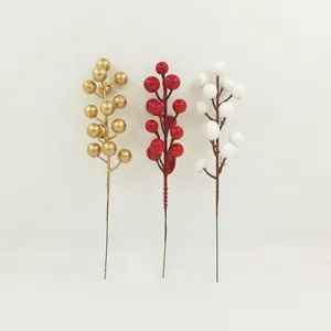 Detailweergave van drie decoratieve kunstmatige kerstbessen in goud, rood en wit.