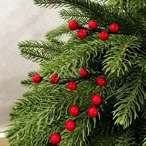 Gros plan d'aiguilles de pin artificielles avec baies de Noël rouges pour le bricolage.