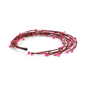 Close-up of decorative artificial brown vine with small pink berries for DIY craft