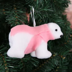 Close-up of white plush polar bear ornament with pink scarf on Christmas tree