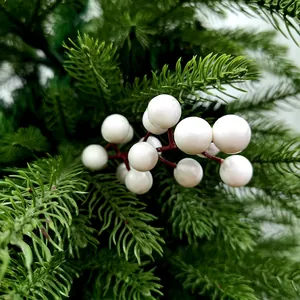 Detailopname van witte kunstmatige kerstbessen op een realistische dennentak
