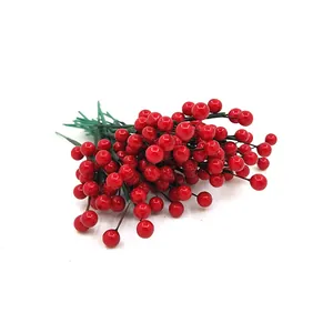 Gros plan de tiges de baies de Noël artificielles rouges pour décorations de fête.