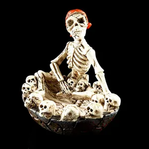 Dettaglio di un portacenere in resina a forma di teschio con scheletro di un pirata.