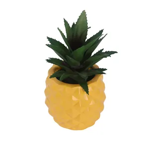 Close-up of artificial green succulent plant in a yellow resin pineapple shaped pot