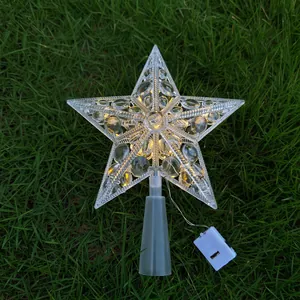 Detailansicht einer leuchtenden LED-Weihnachtsbaumpitze in Sternform auf grünem Gras