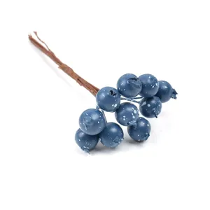 Primer plano de bayas azules artificiales para coronas y decoraciones navideñas.