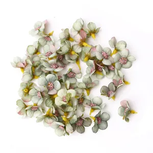 Dettaglio di mini margherite in seta verde salvia da 2 cm con centri rosa