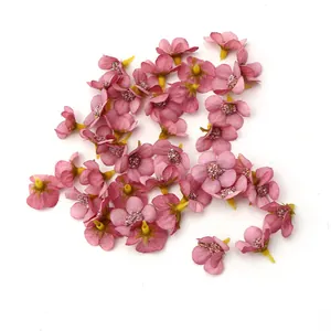 Vista dettagliata di mini capolini di margherita in seta rosa da 2 cm per decor.