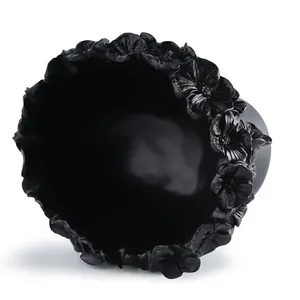 Close-up view of a black artistic flower pot with detailed floral carvings on the rim