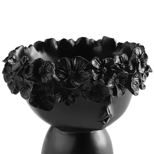 Detailed close-up of a matte black resin flower pot with an artistic floral crown design