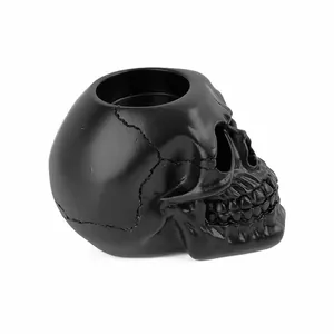 Detail view of a matte black resin skull ashtray with intricate bone carvings