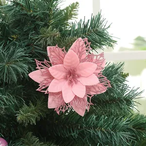 Dettaglio di un fiore di Natale artificiale rosa glitterato su un ramo di pino