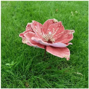 Gros plan d'un magnolia artificiel en velours rose avec des paillettes sur de l'herbe verte