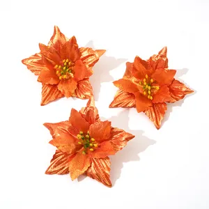 Detailed view of three glittery orange artificial poinsettia flowers for Christmas.