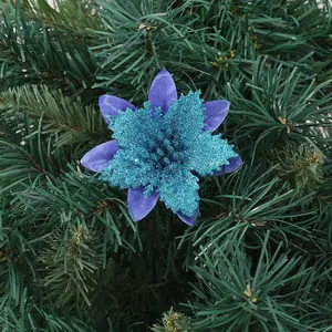 Close-up of a vibrant blue glitter artificial Christmas flower nestled in green pine branches