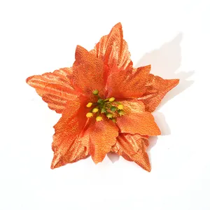 Close-up of a glittery orange Christmas poinsettia flower decoration on white backdrop