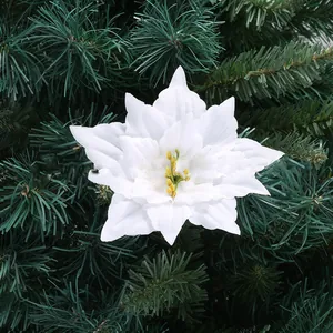 Detail view of a white artificial poinsettia flower on green Christmas tree branches.