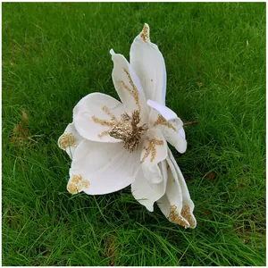 Gros plan d'une fleur de magnolia artificielle en tissu blanc pailleté d'or