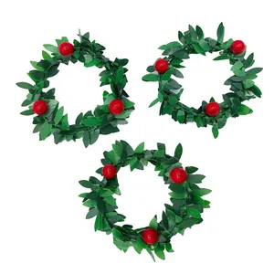 Detail of three green leafy Christmas napkin rings with decorative red berries