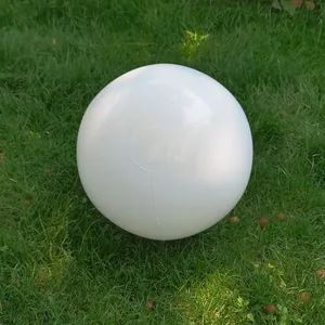 Close-up detailed view of a durable white inflatable PVC beach ball resting on lush green grass