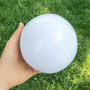 Close-up of a white PVC inflatable beach ball held in hand over green grass.